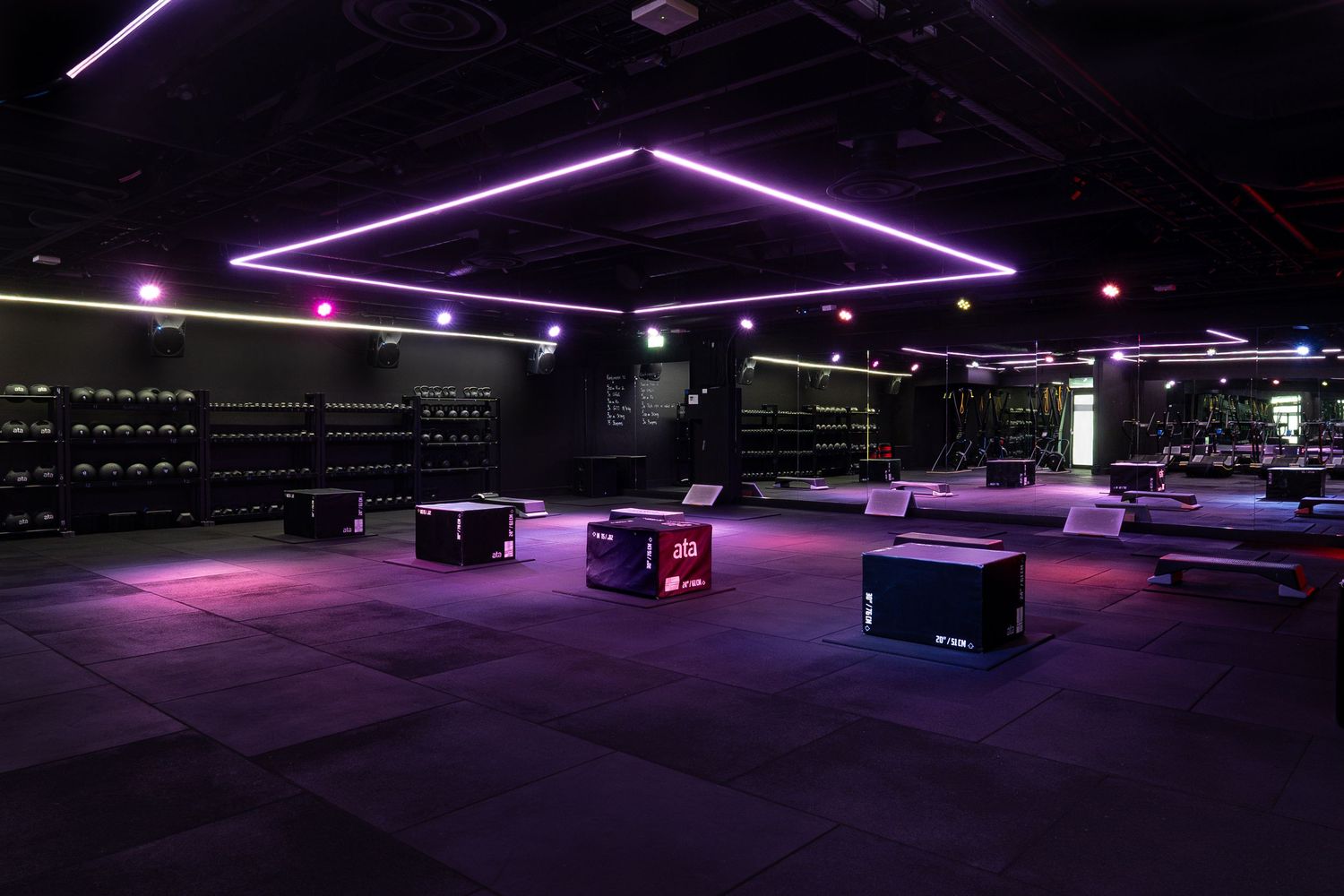 Minimalist gym interior with purple accent lighting and modern exercise equipment.