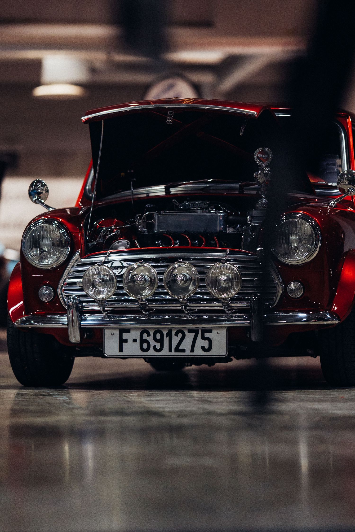 Detailed view of classic car engines and front grills in red at an auto exhibition.