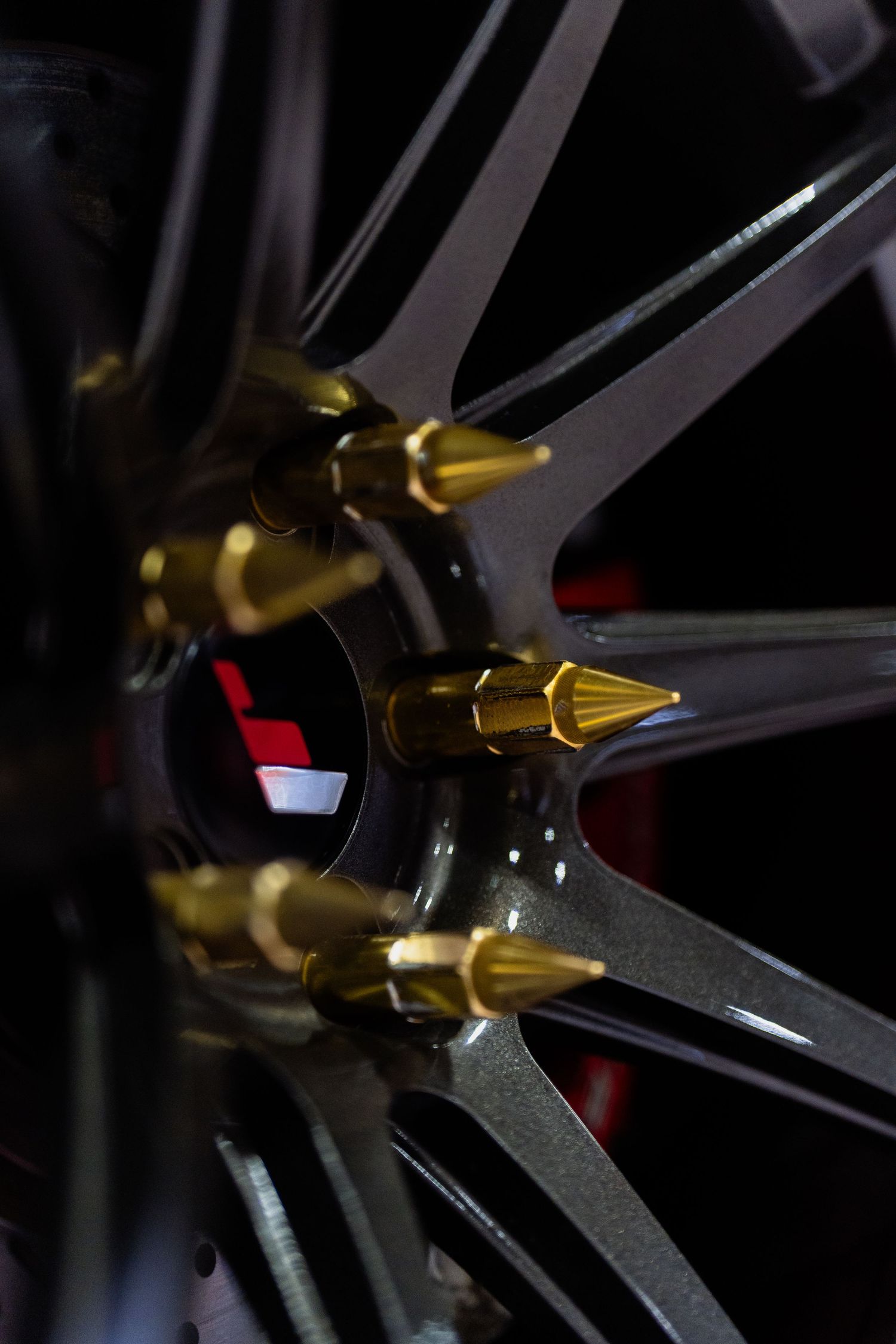 Detailed shot of black wheel spokes with gold spiked lug nuts.