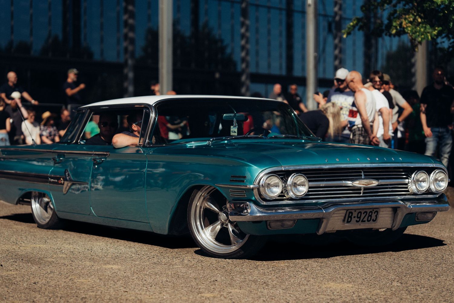 Teal classic Chevrolet sedan with custom wheels parked at an outdoor car show.