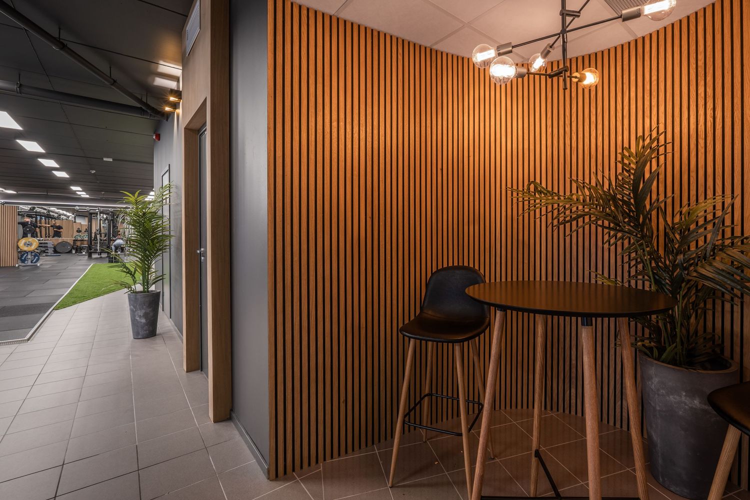 Contemporary bistro nook with wooden slat walls, high table and modern black bar stools.