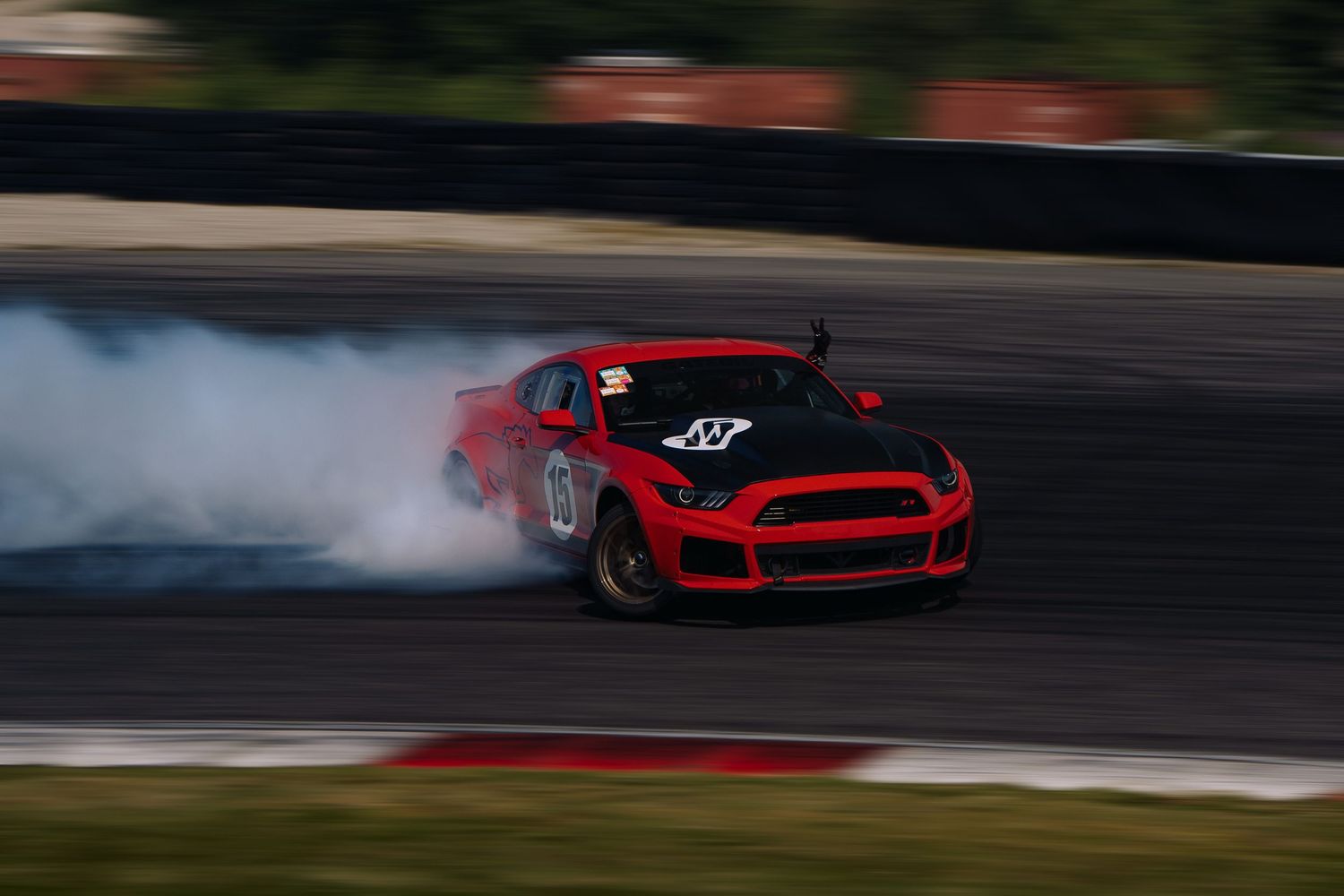 Red sports cars drifting in formation on a race track with smoke trailing behind them.