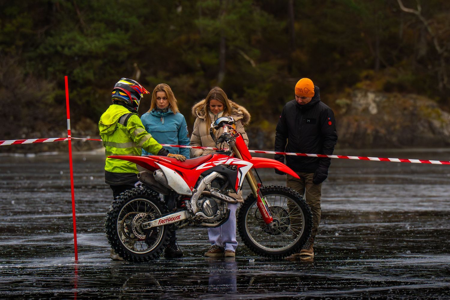 A sequence of action shots showing a motorcycle stunt rider performing a jump over a wet surface.