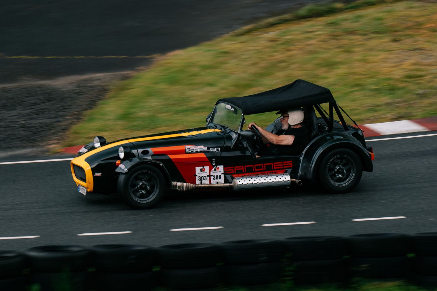 Racing cars navigate a challenging track turn during a competitive motorsport event at high speeds.