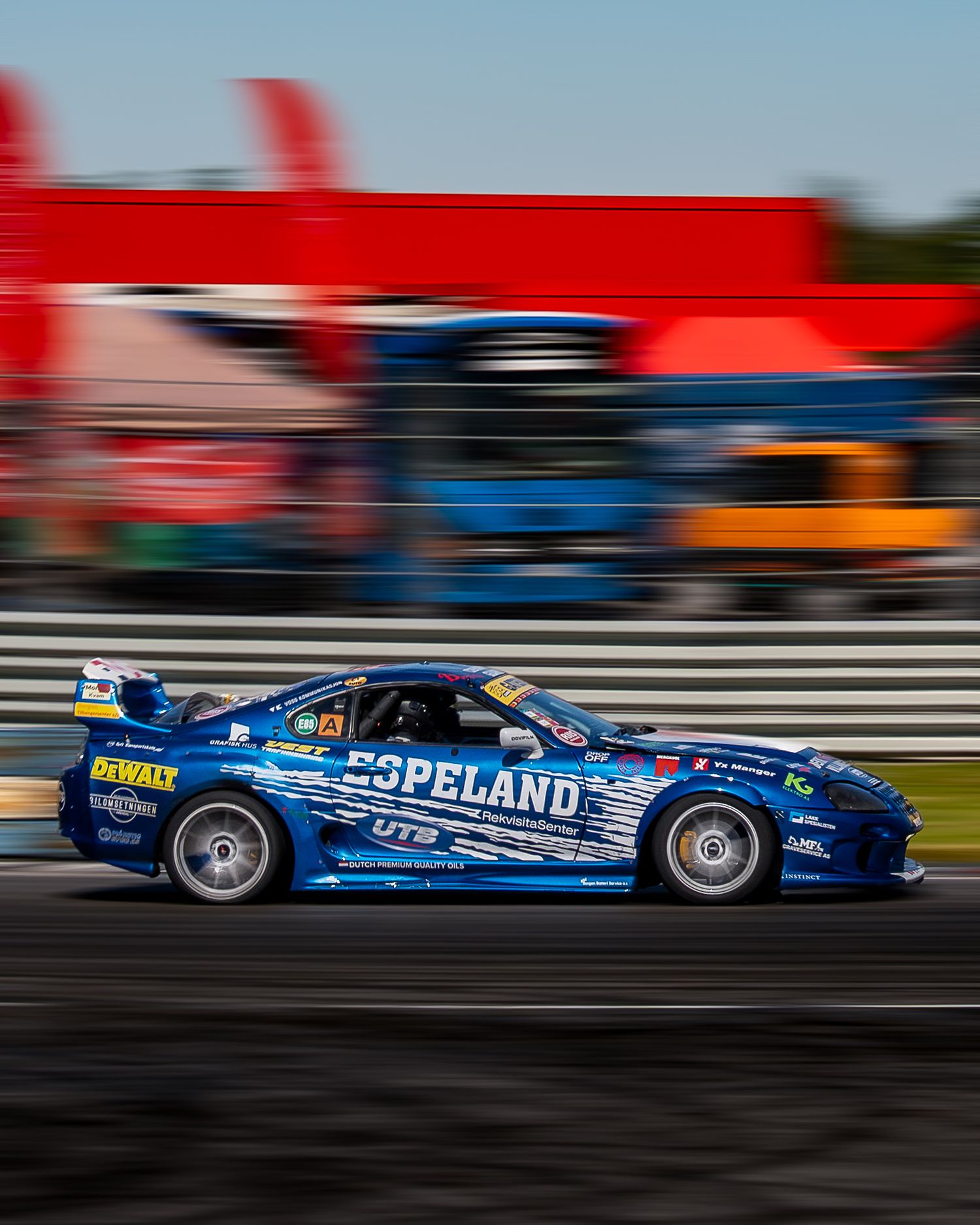 A blue racing car with Copeland branding speeds along a racetrack with motion blur in the background.