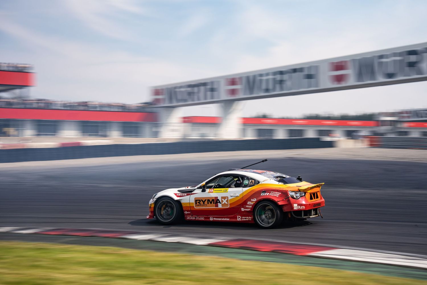 A sequence of racing cars speeding around a track during a motorsport competition.