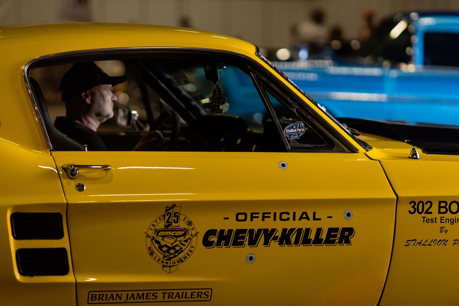 Yellow vintage racing car with 'Chev Killer' lettering displayed at automotive event.