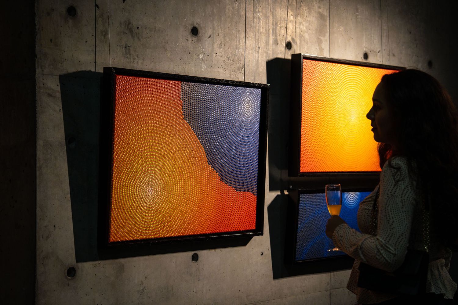 Visitor examines modern abstract artwork featuring bold orange and blue geometric shapes.
