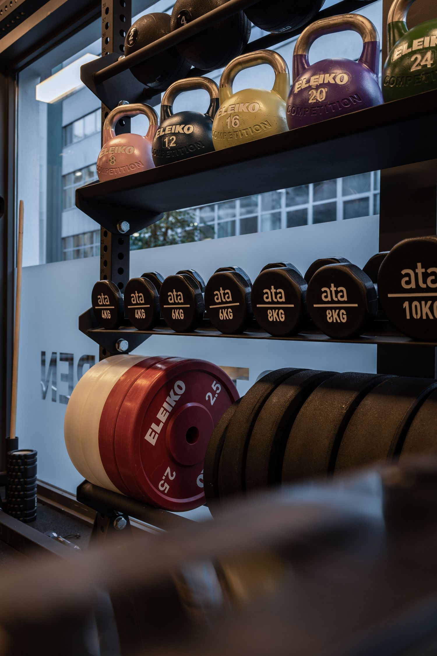 Colorful kettlebells and weight plates arranged on industrial shelving.