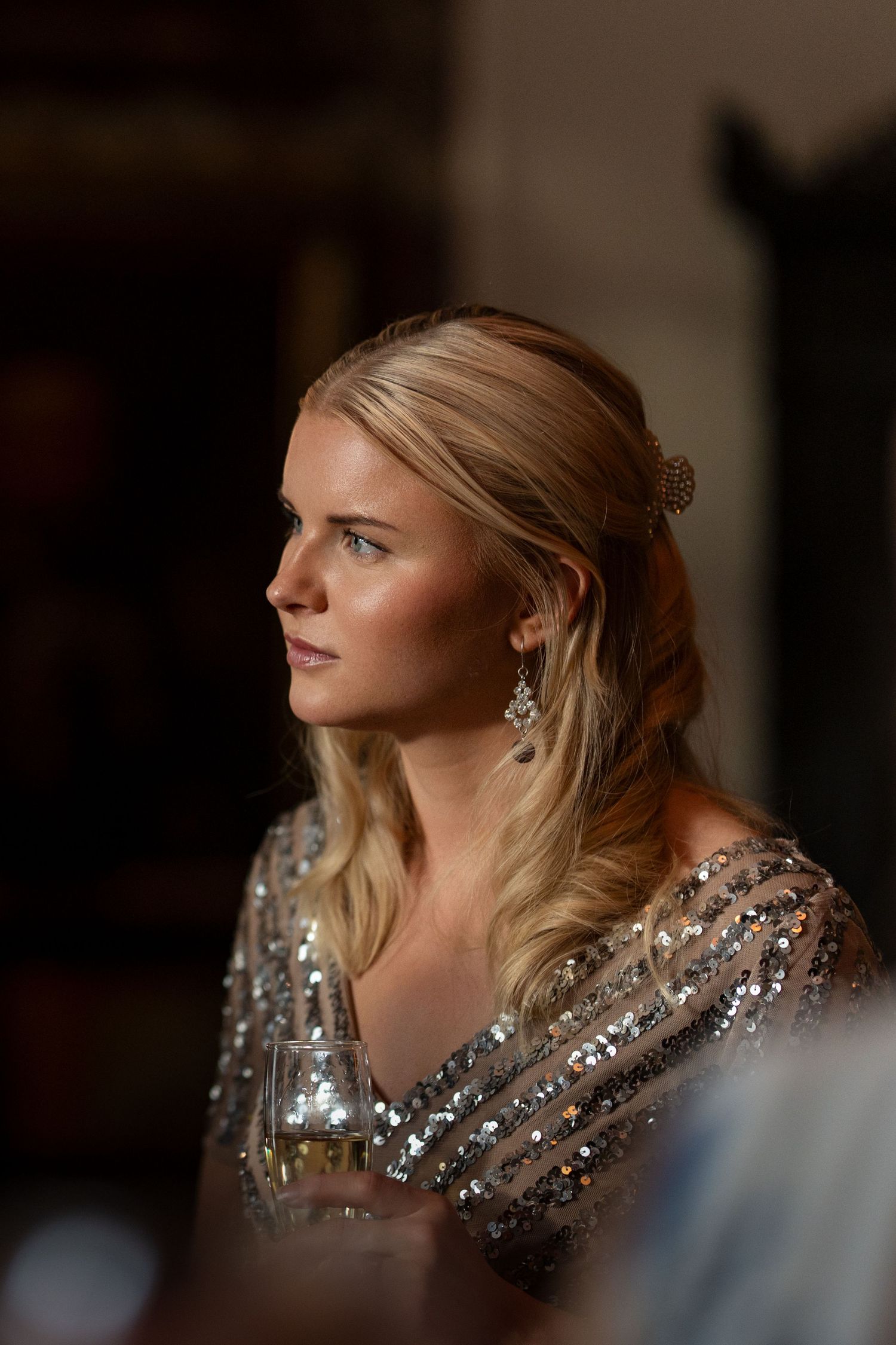 Guest in sparkly silver dress shown in profile at evening event.