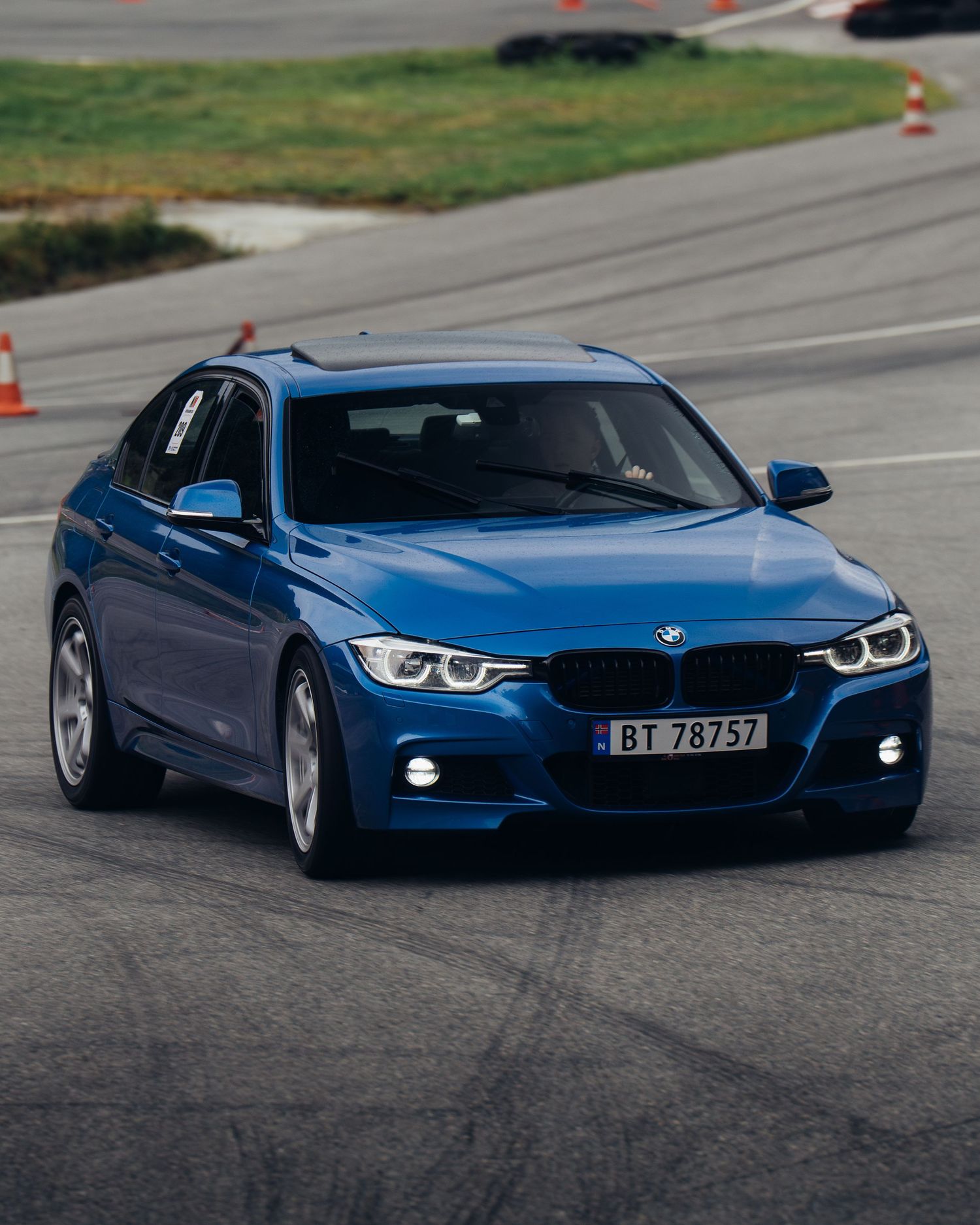 A blue BMW 3 series sport sedan drifting on a track with cones visible in multiple dynamic action shots.