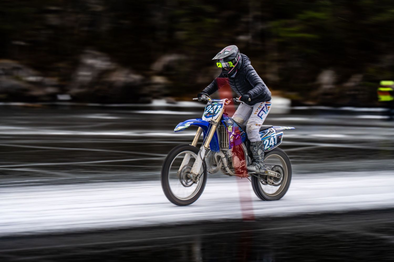 Sequence of motorcycle rider jumping and performing aerial stunts on snowy winter terrain at high speed.