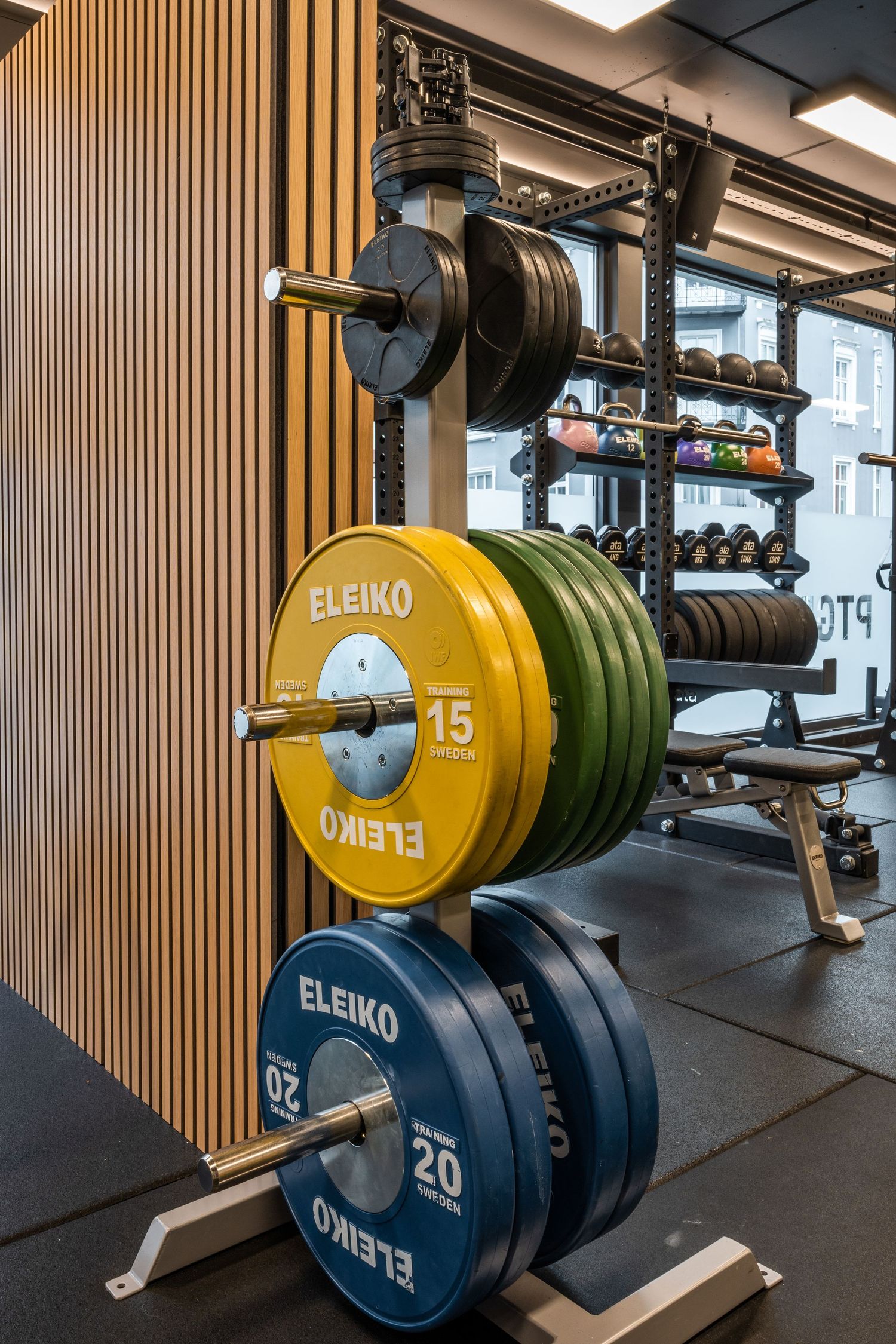 Stack of Eleiko weight plates mounted on a rack against wooden slat wall paneling.