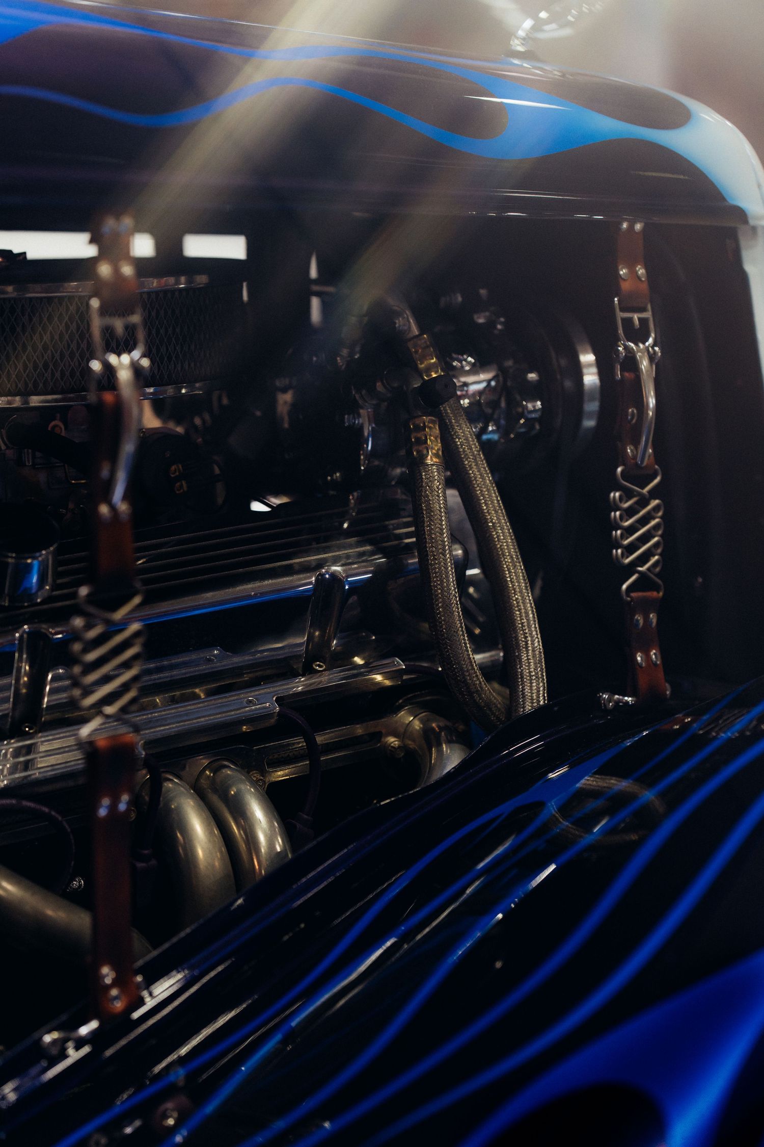 Blue tinted engine bay detail showing mechanical components and chrome finishing.