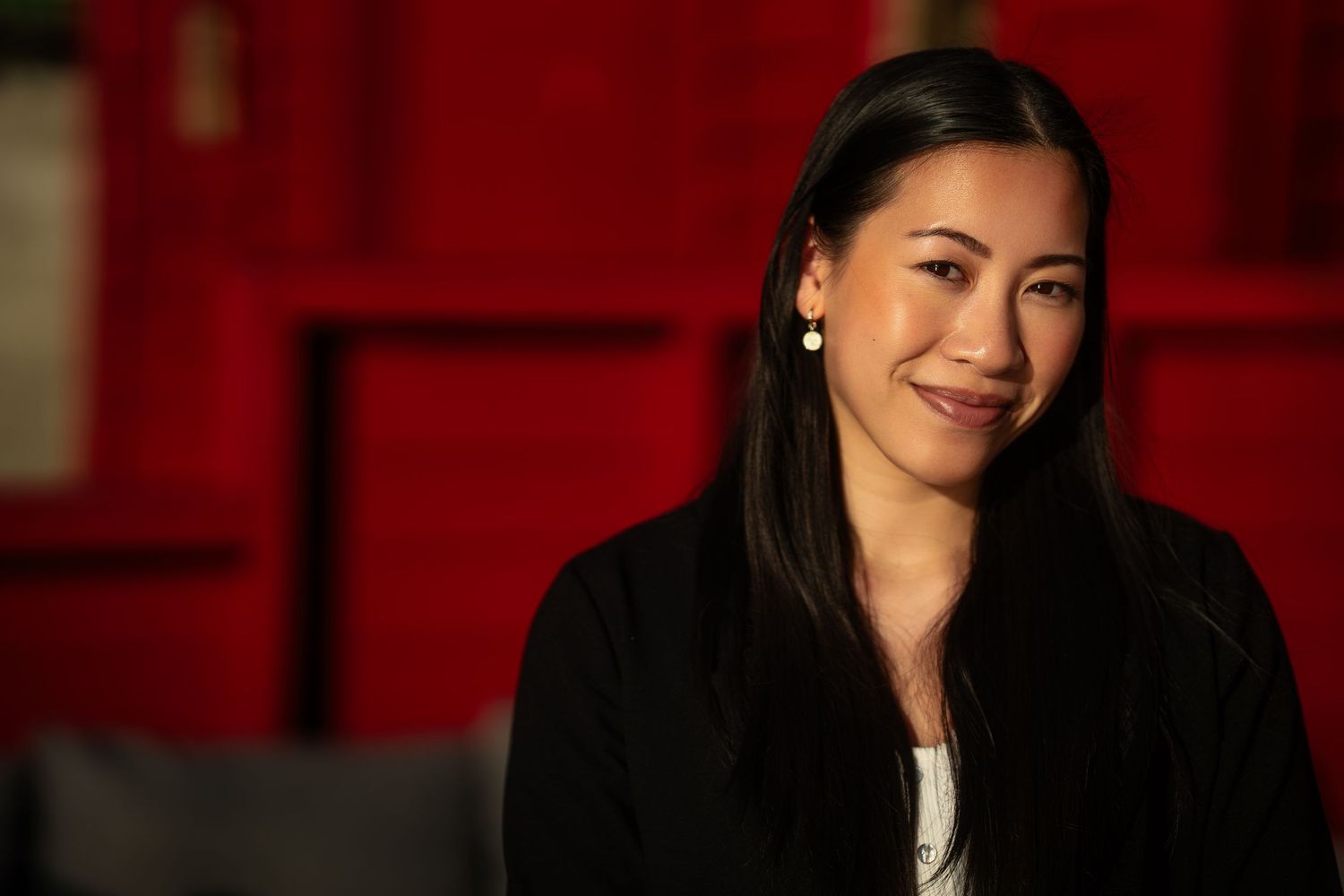 A portrait against a red background captures warm lighting and dramatic shadows.