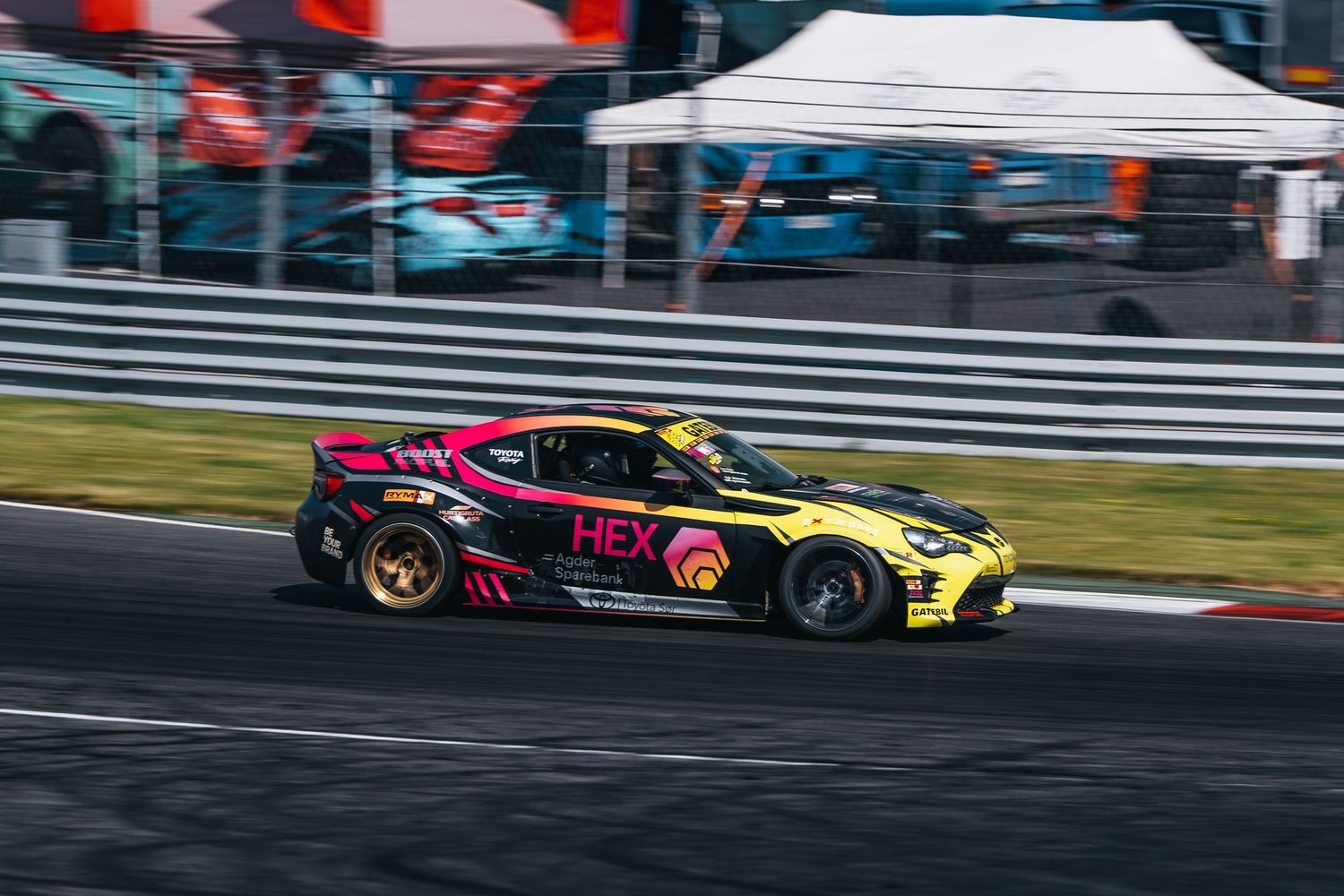 Race cars speed through a racetrack curve during a high-speed motorsport competition.
