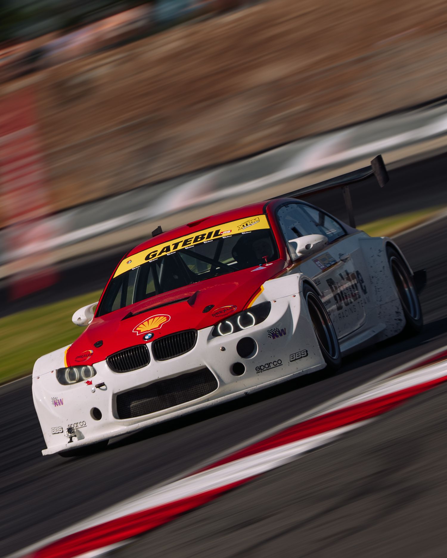Multiple BMW race cars speed around a racetrack corner in a dynamic motion-blurred sequence.