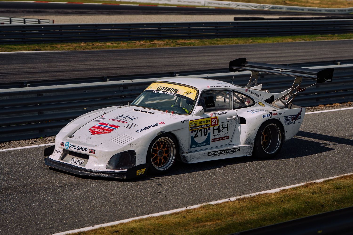 White Porsche 911 GT3 race cars line up on a racetrack during a motorsport competition event.
