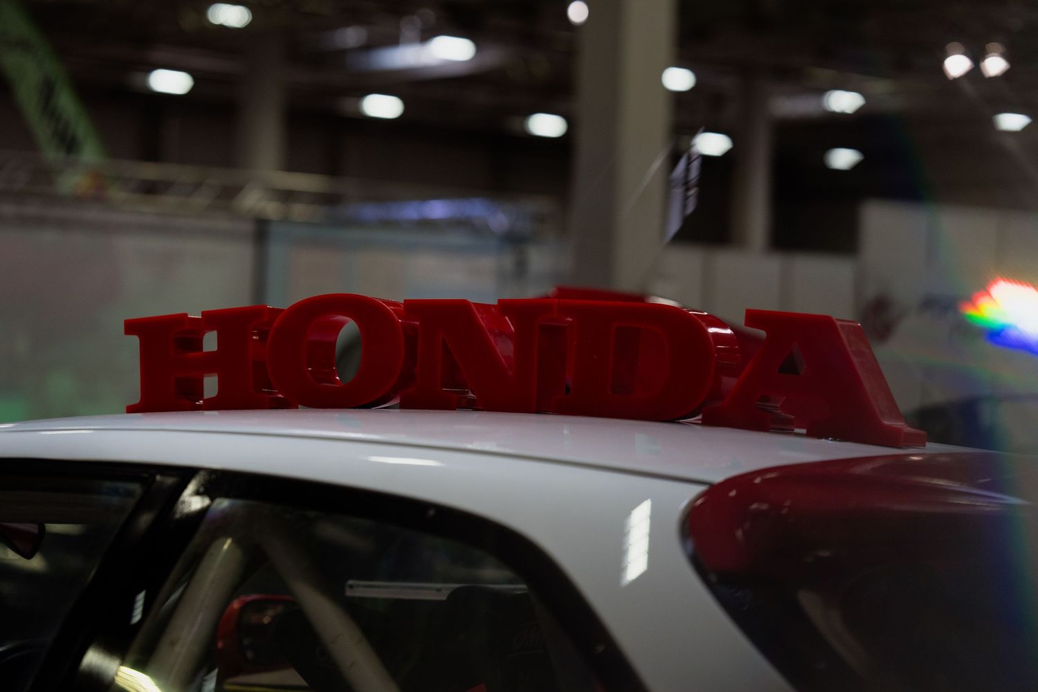 Honda text displayed in red lettering on white car surface.