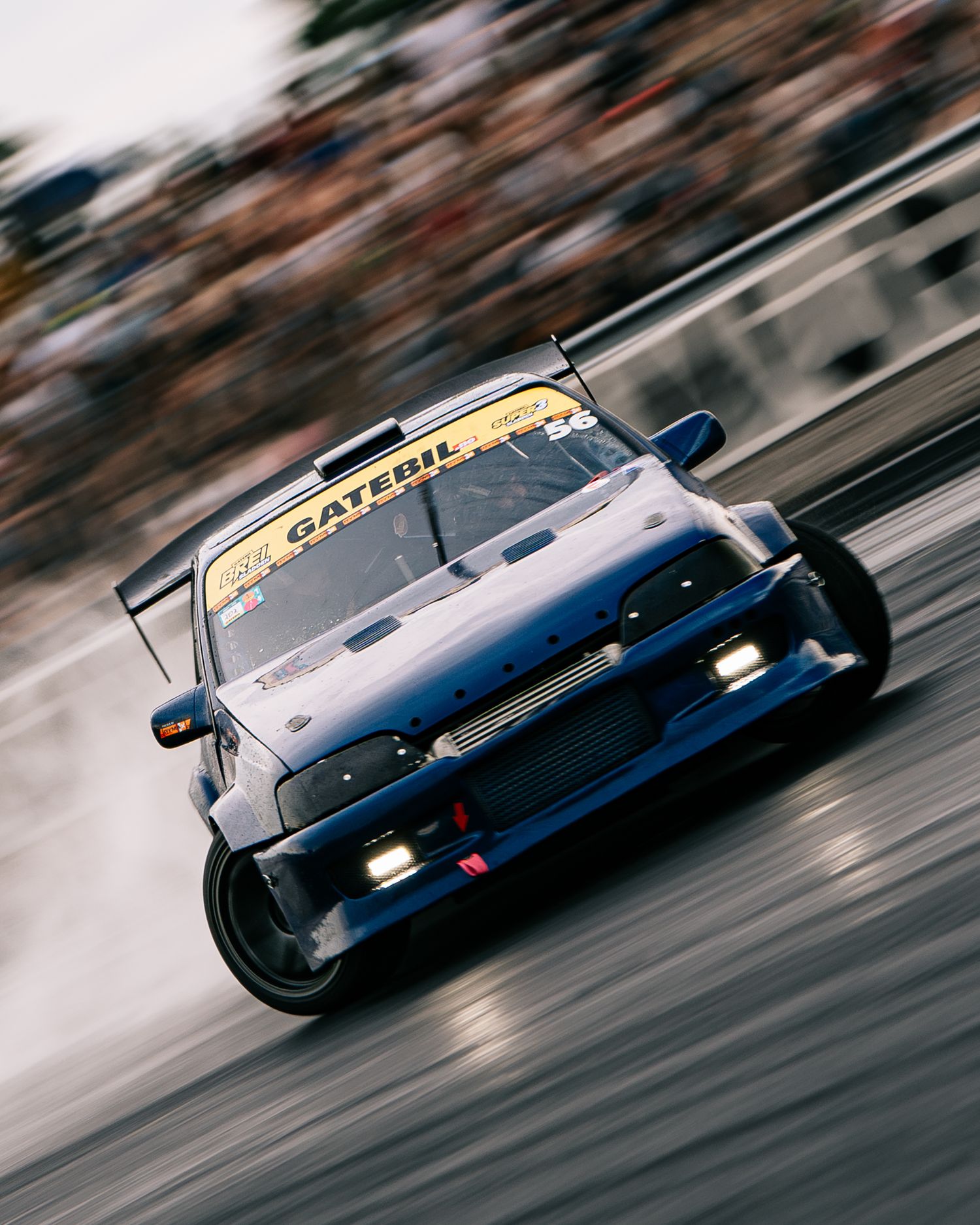 Motion-blurred racing shots of a dark blue Porsche race car speeding along a racetrack.