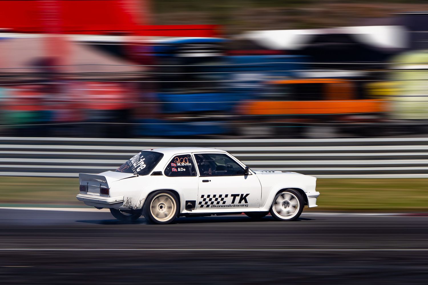 Motion-blurred race cars speeding past on a track with vibrant red, blue and white streaks in the background.