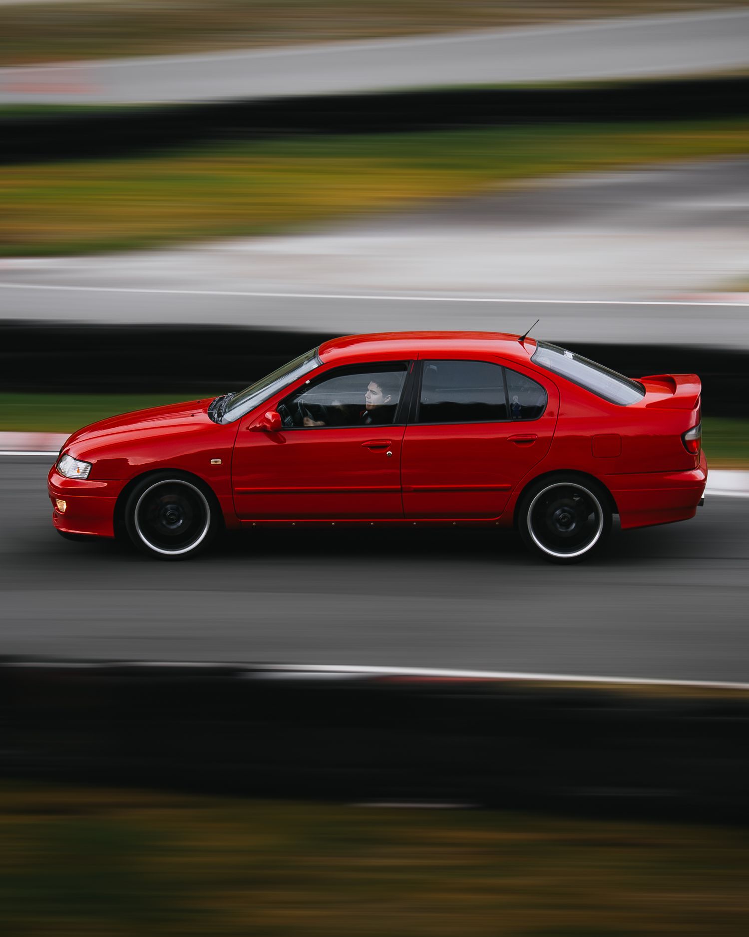 A red sports car in motion on a racetrack with motion blur effect creating a dynamic and dramatic scene.