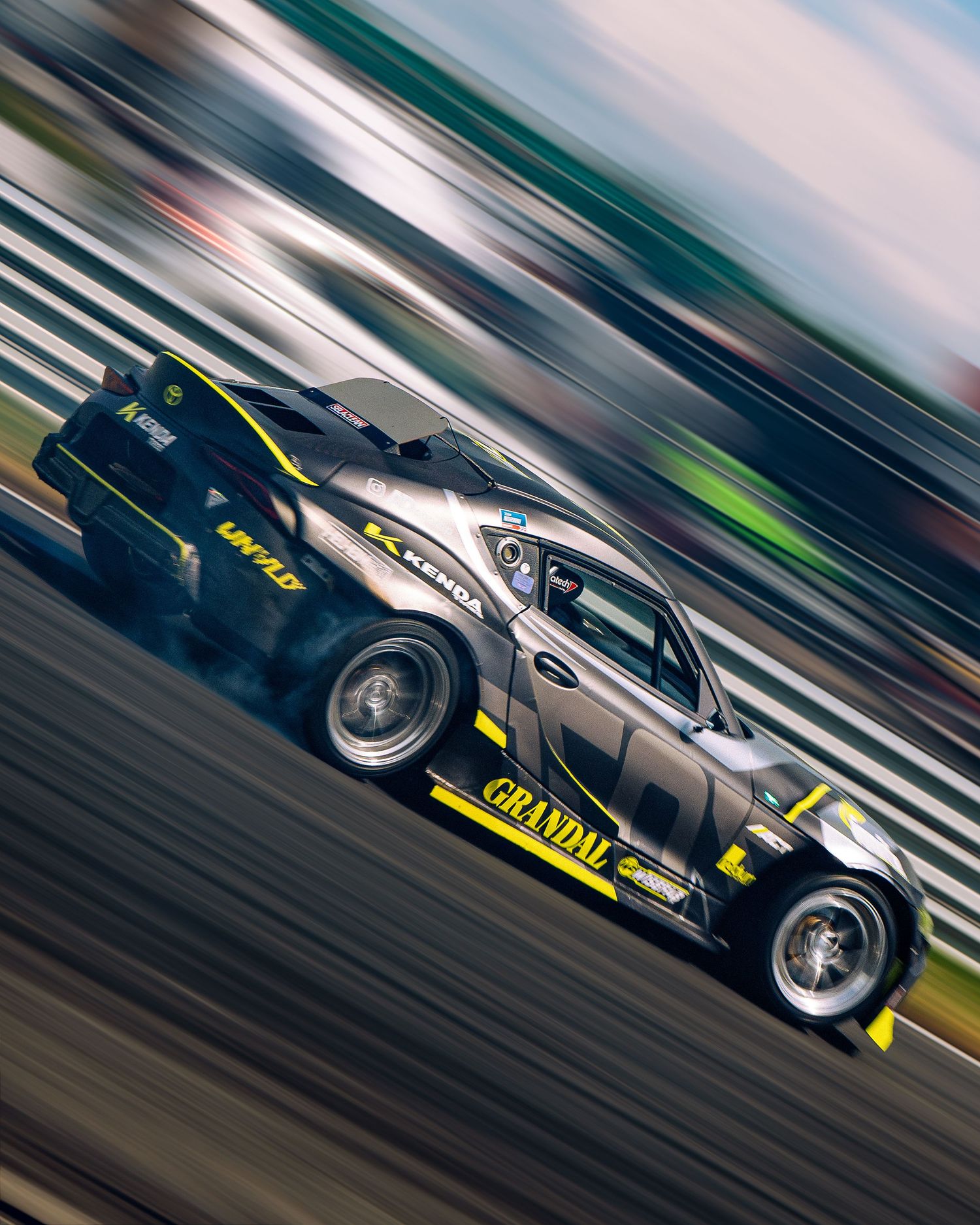 Blurred motion shots of sports cars drifting on a racetrack with dramatic panning effects showing speed and movement.