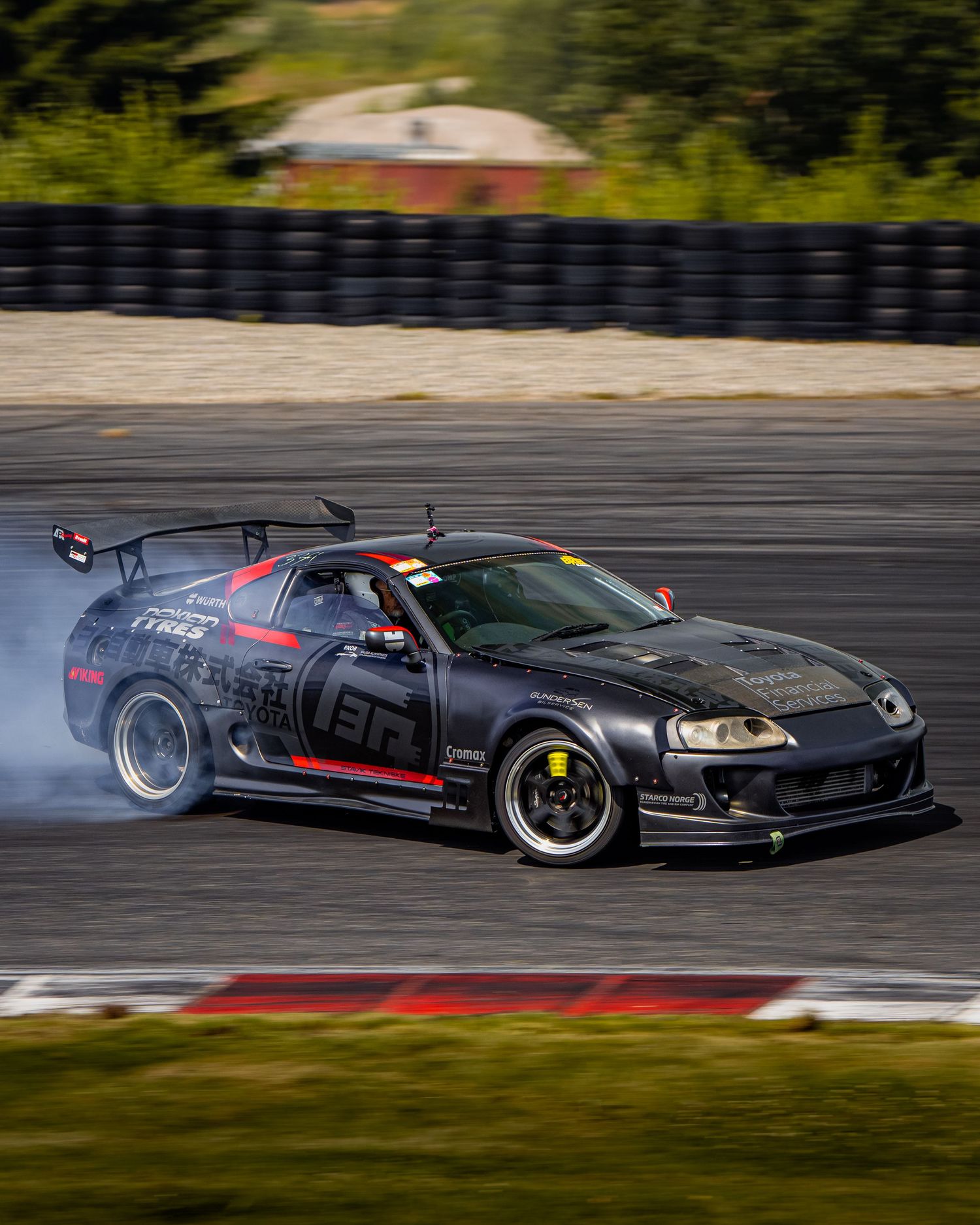 Black modified Honda NSX drifting on a racetrack with smoke trailing from the rear tires.