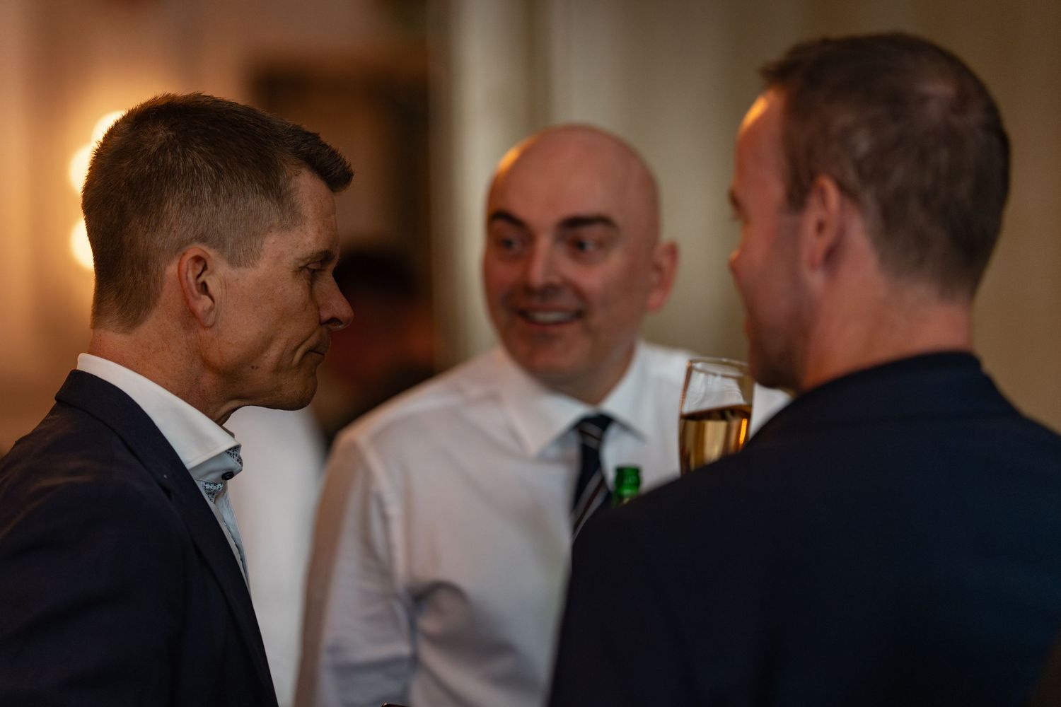 Three guests engaged in lively conversation at an upscale evening gathering.