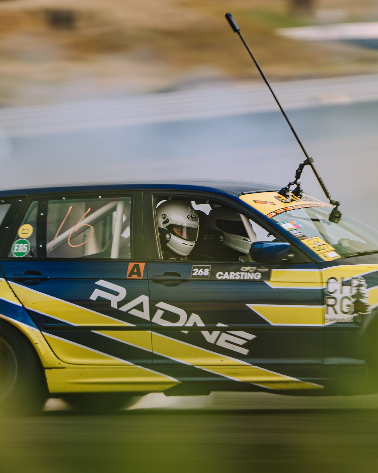 Side view of a yellow and black racing aircraft flying low to the ground during an air race competition.