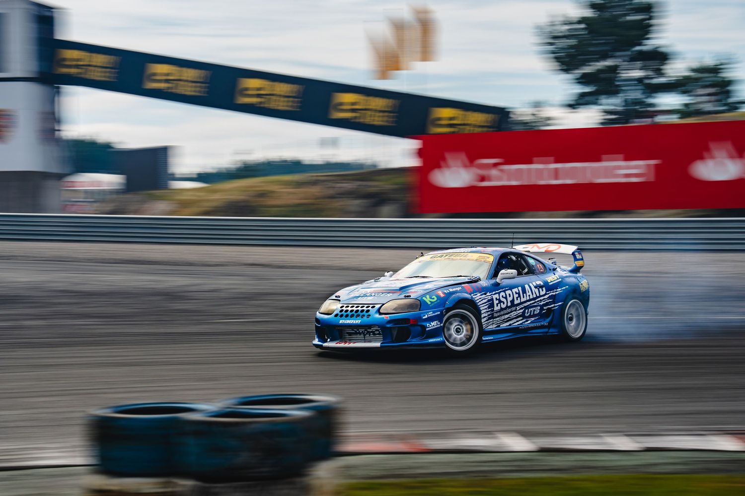 Race cars speed around a track during a competitive motorsport event at high speeds with blurred motion effects.