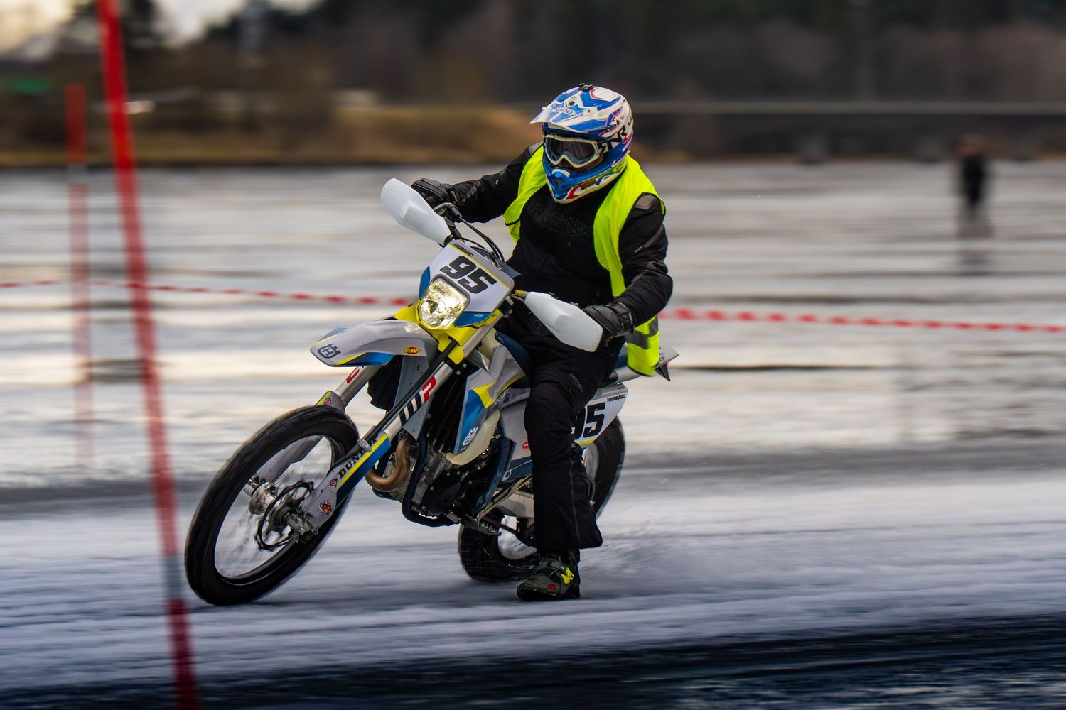 A motorcycle rider leans into a turn on a wet racetrack during a racing competition.