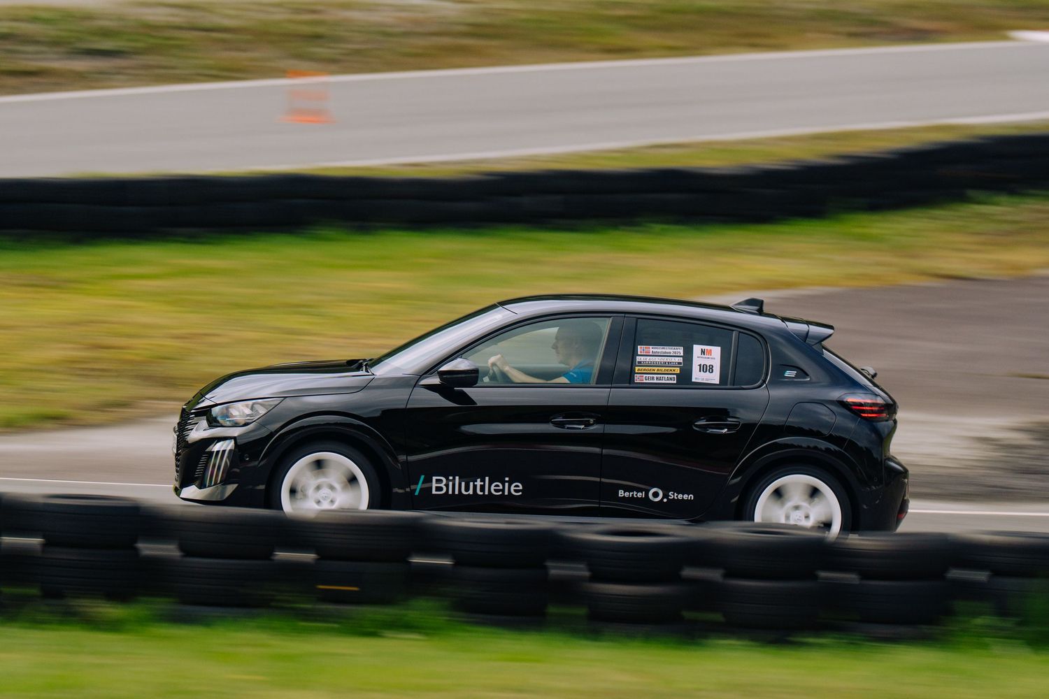 A black luxury car speeds around a racetrack with motion blur visible in the background.