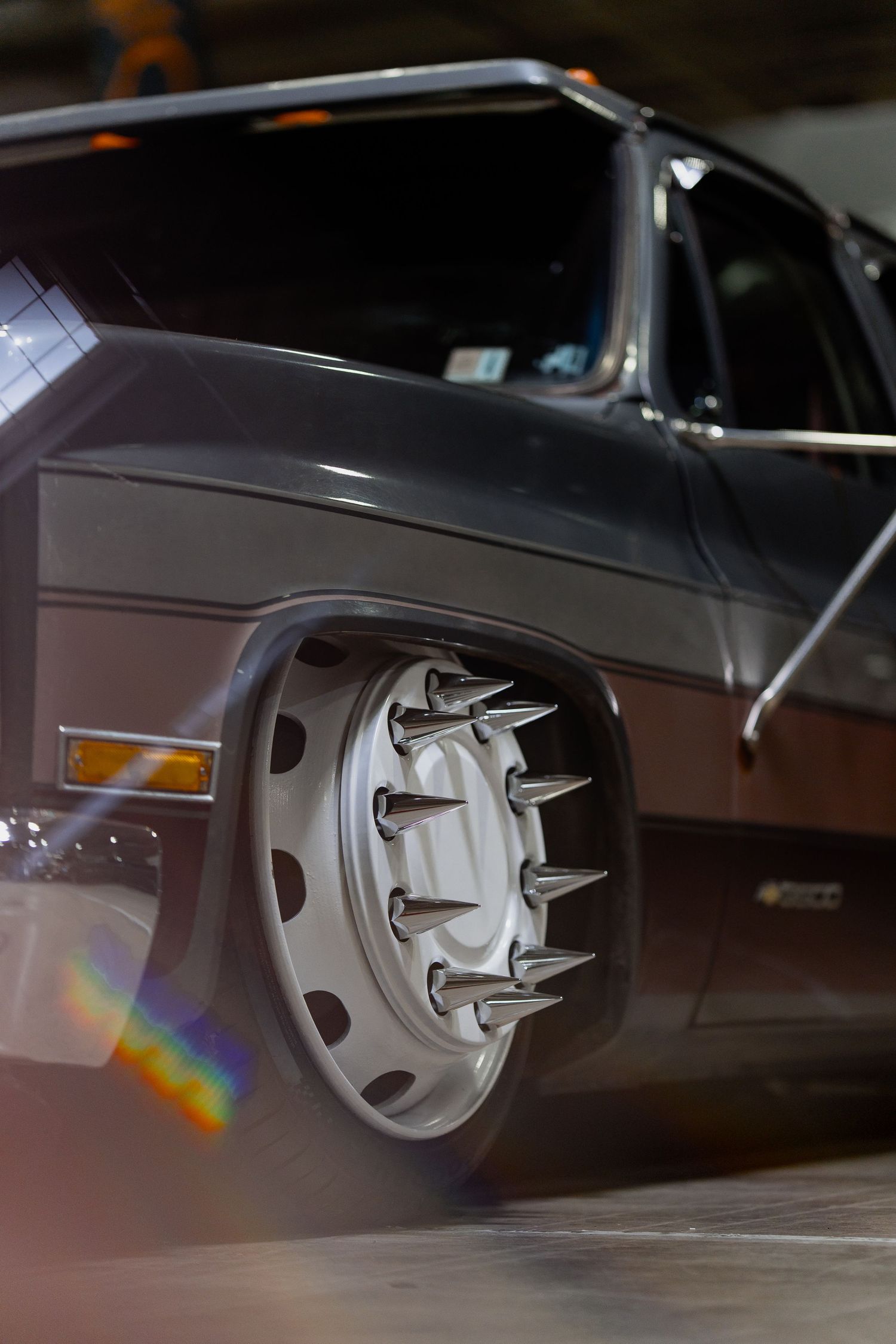 Custom chrome wheel hub with protruding spikes captured in dramatic lighting.