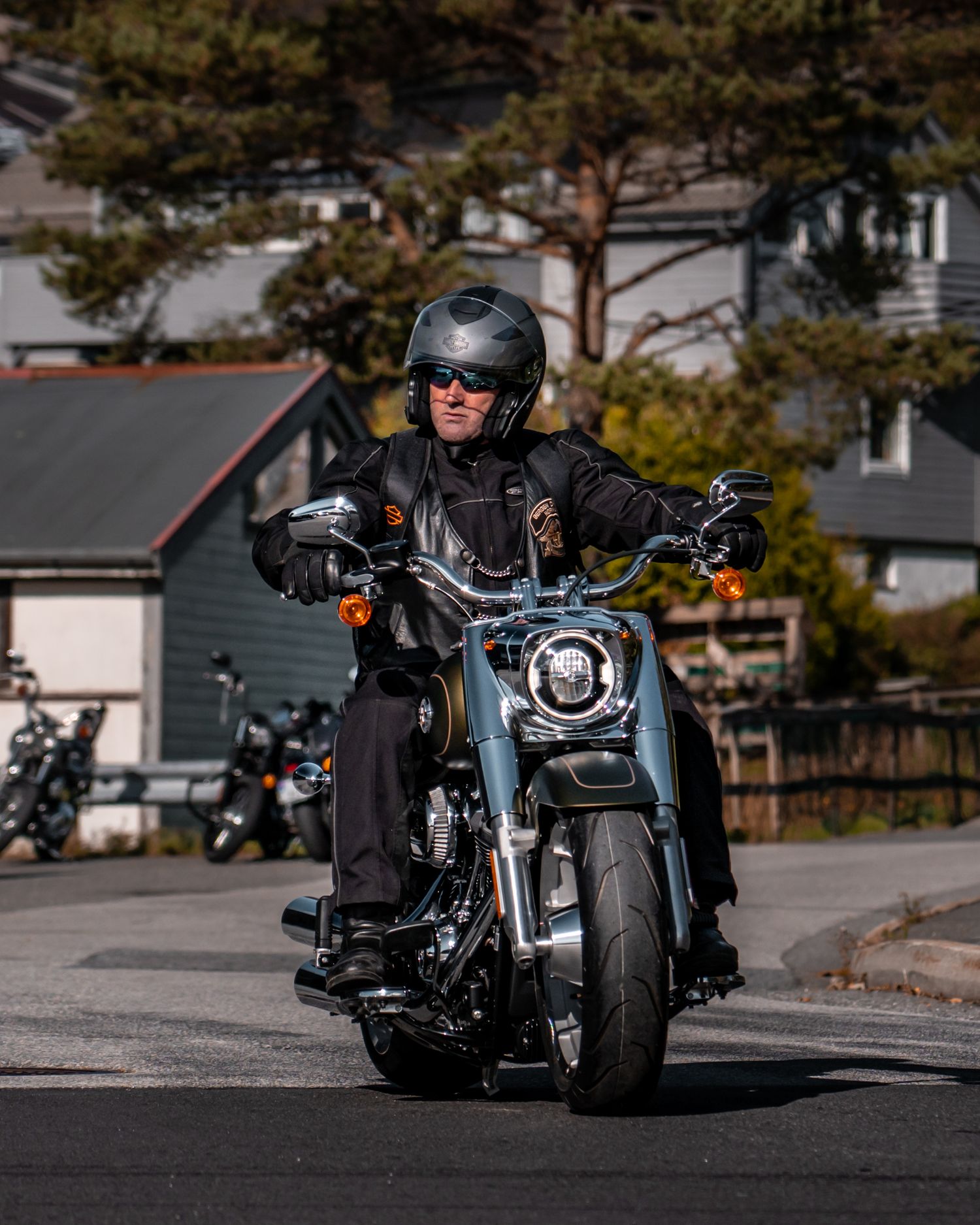 Motorcyclist rides a classic Harley-Davidson cruiser on a suburban street.
