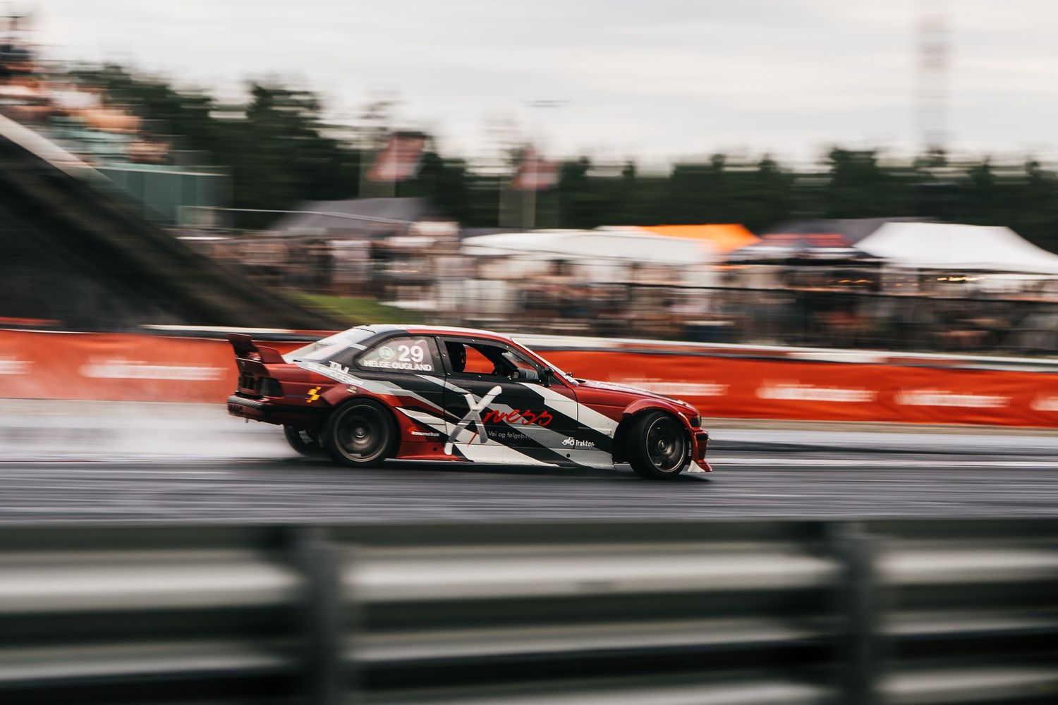 Race cars speed down a track during a professional motorsport competition with motion blur effects visible.