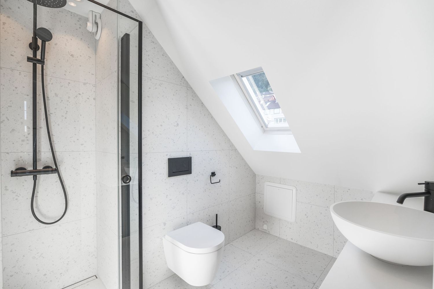 Modern attic bathroom with skylight, walk-in shower, and floating white fixtures.