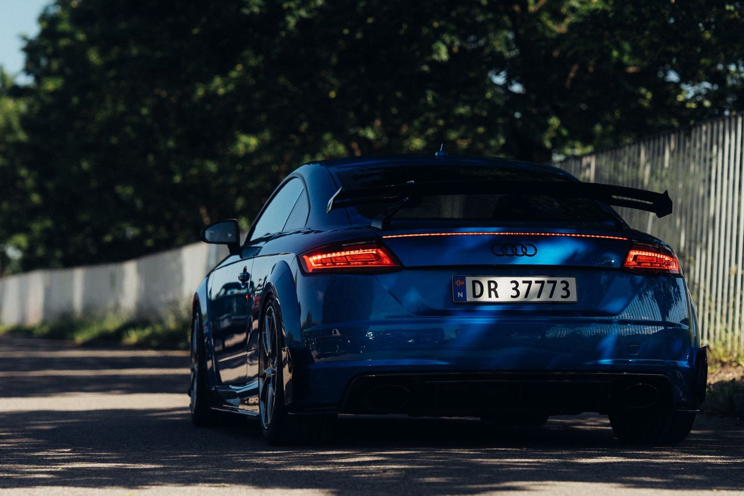 Sports cars with bright tail lights photographed in low light conditions.