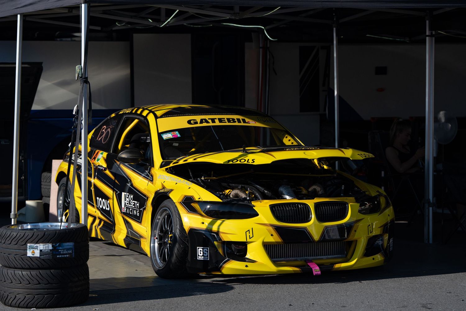 Yellow and black racing cars lined up in a garage or showroom displaying high-performance motorsport vehicles.