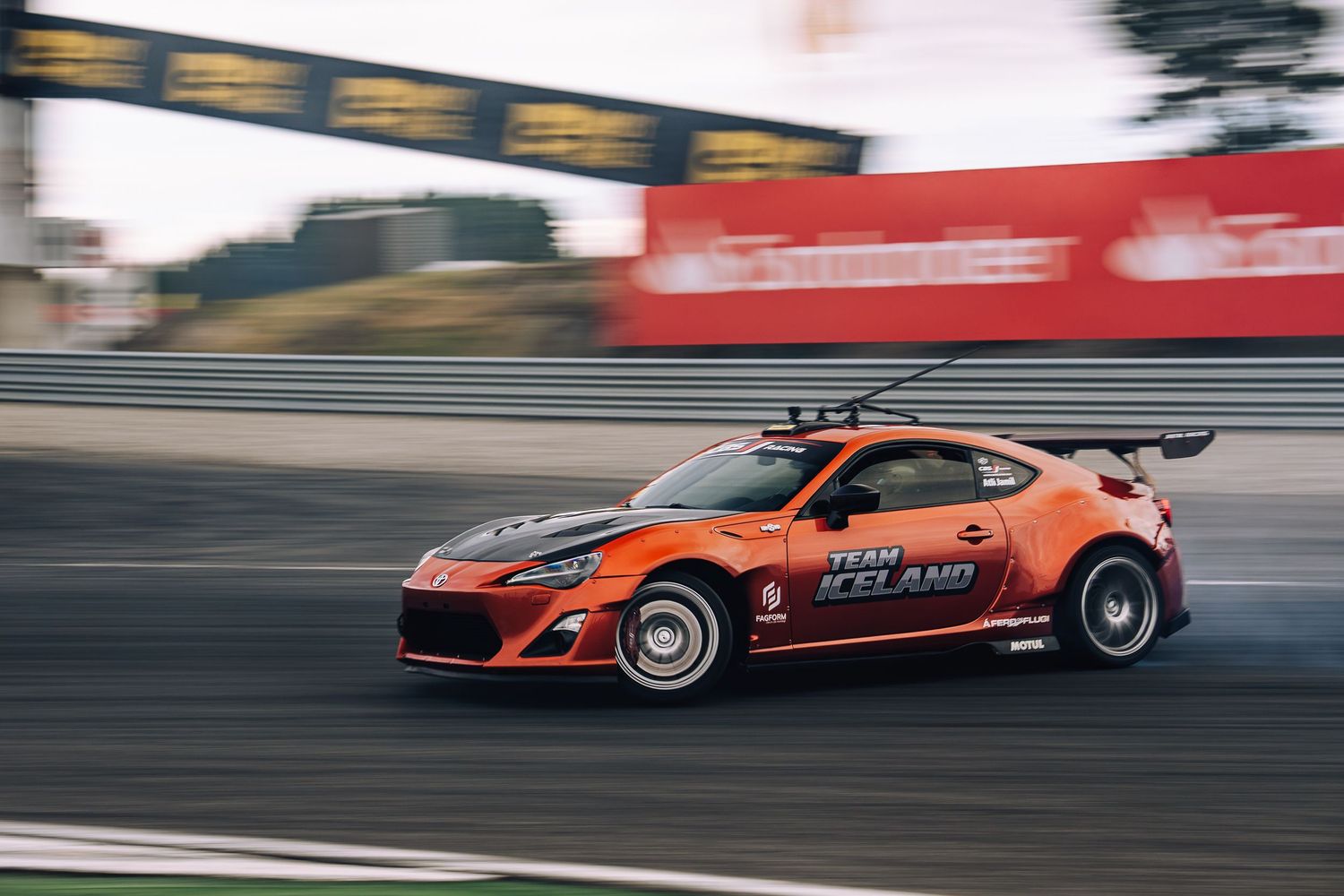 High-speed racing cars streak across a racetrack in a dynamic sequence of motion-blurred action shots.