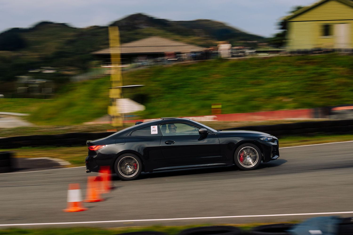 A black BMW M8 Gran Coupe drives on a winding mountain road during a performance test session.