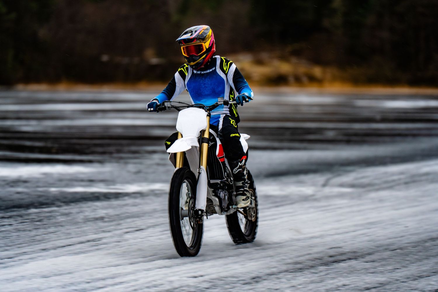 A motorcycle rider speeds across a frozen lake surface creating an exciting action sequence.