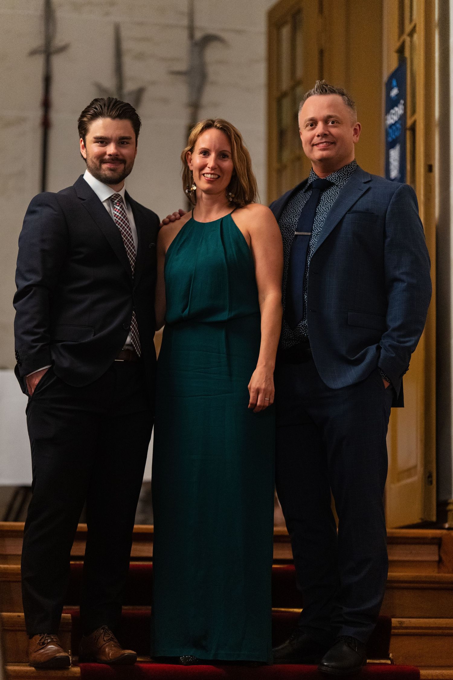 Group photo showing elegantly dressed guests in formal attire at an upscale event venue.