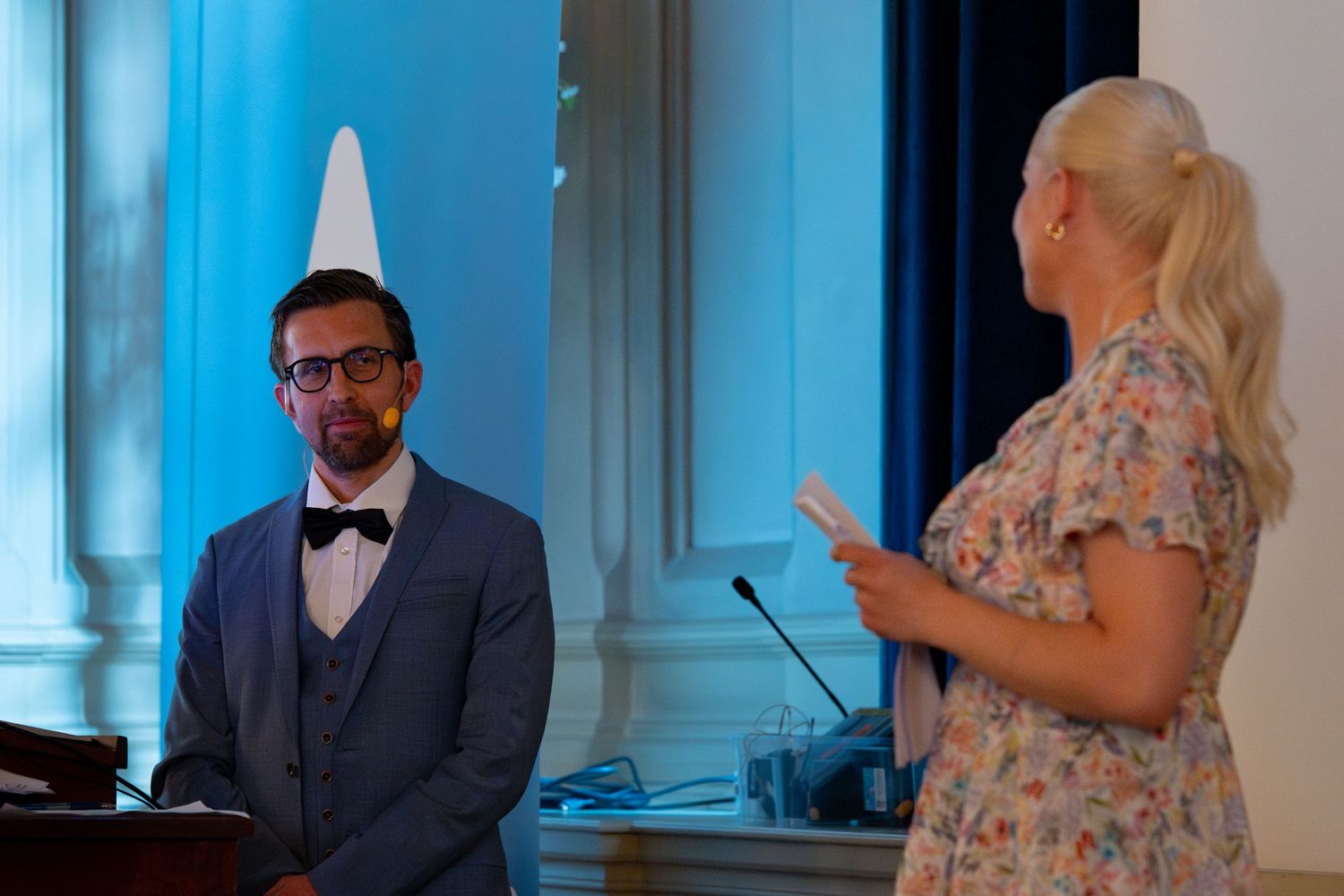 Wedding guests enjoying formal celebration in bright room with blue lighting.