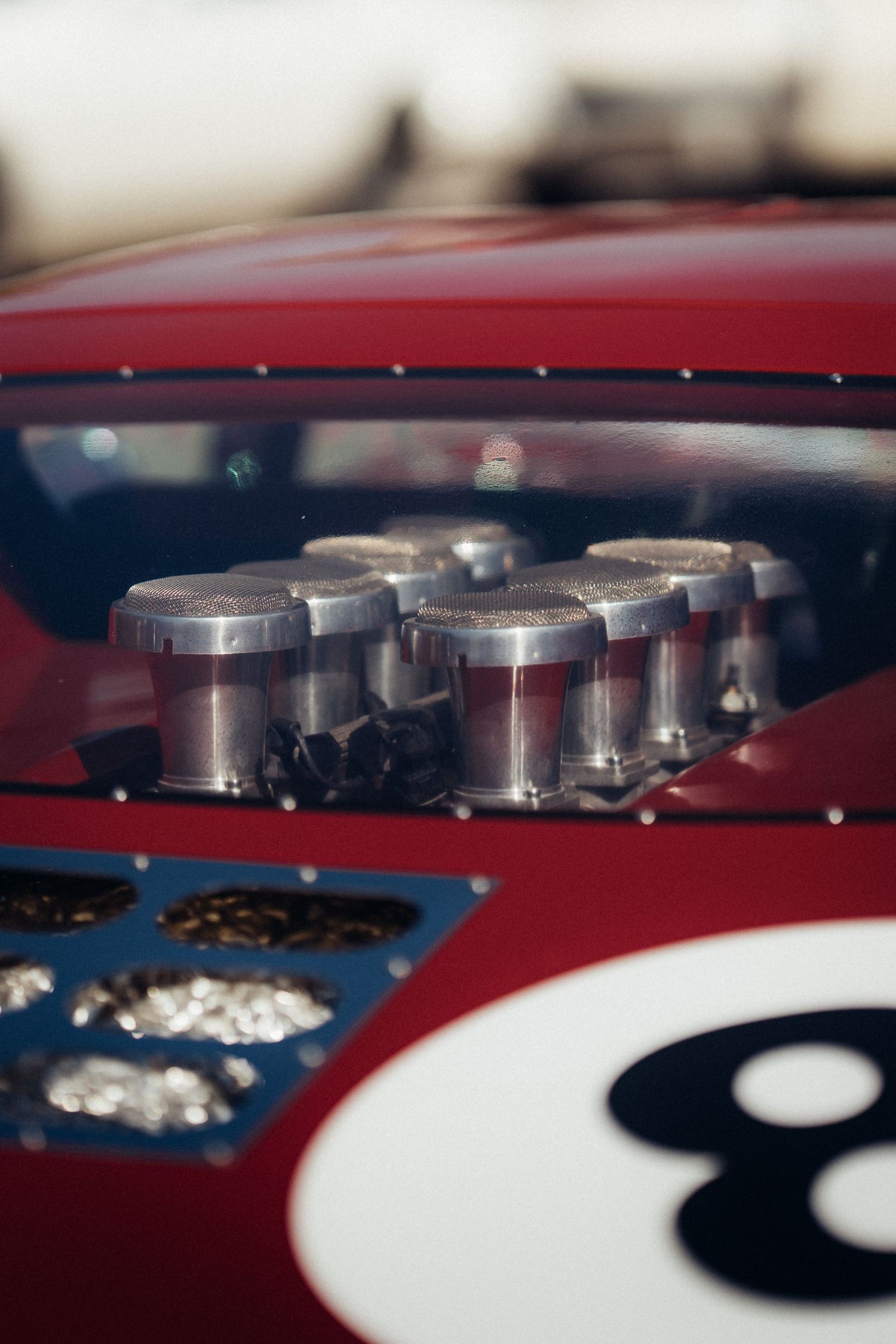 Racing car detail showing multiple carburetors and number 8 decal on red bodywork.