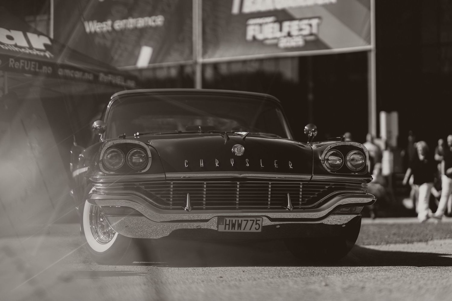 Vintage Chrysler automobile photographed in black and white in front of a building entrance.