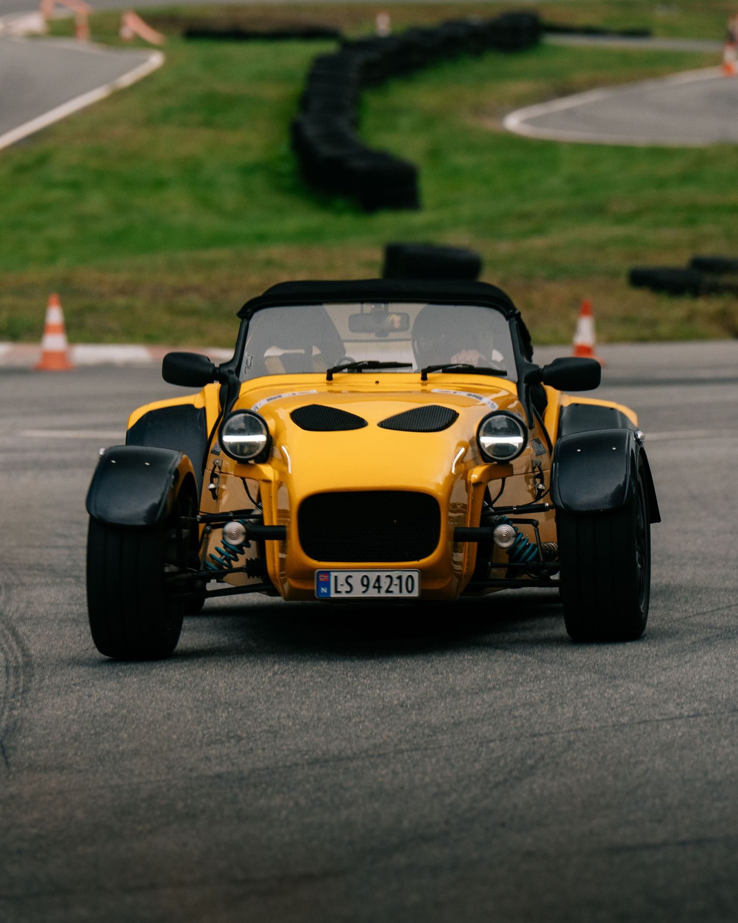 A bright yellow Donkervoort sports car with exposed wheels shown from multiple angles on an asphalt surface.