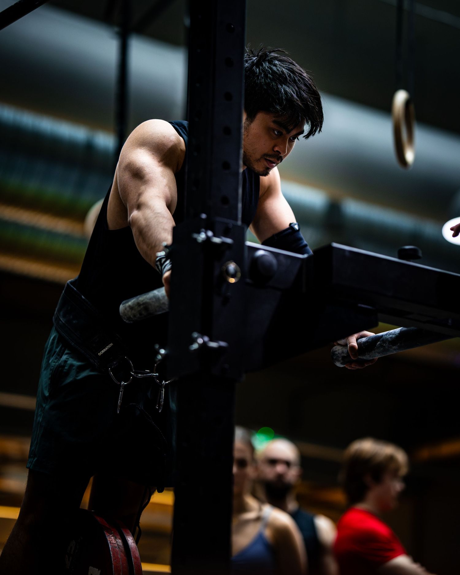 Athlete performing strength exercise on parallel bars in dark gym environment.