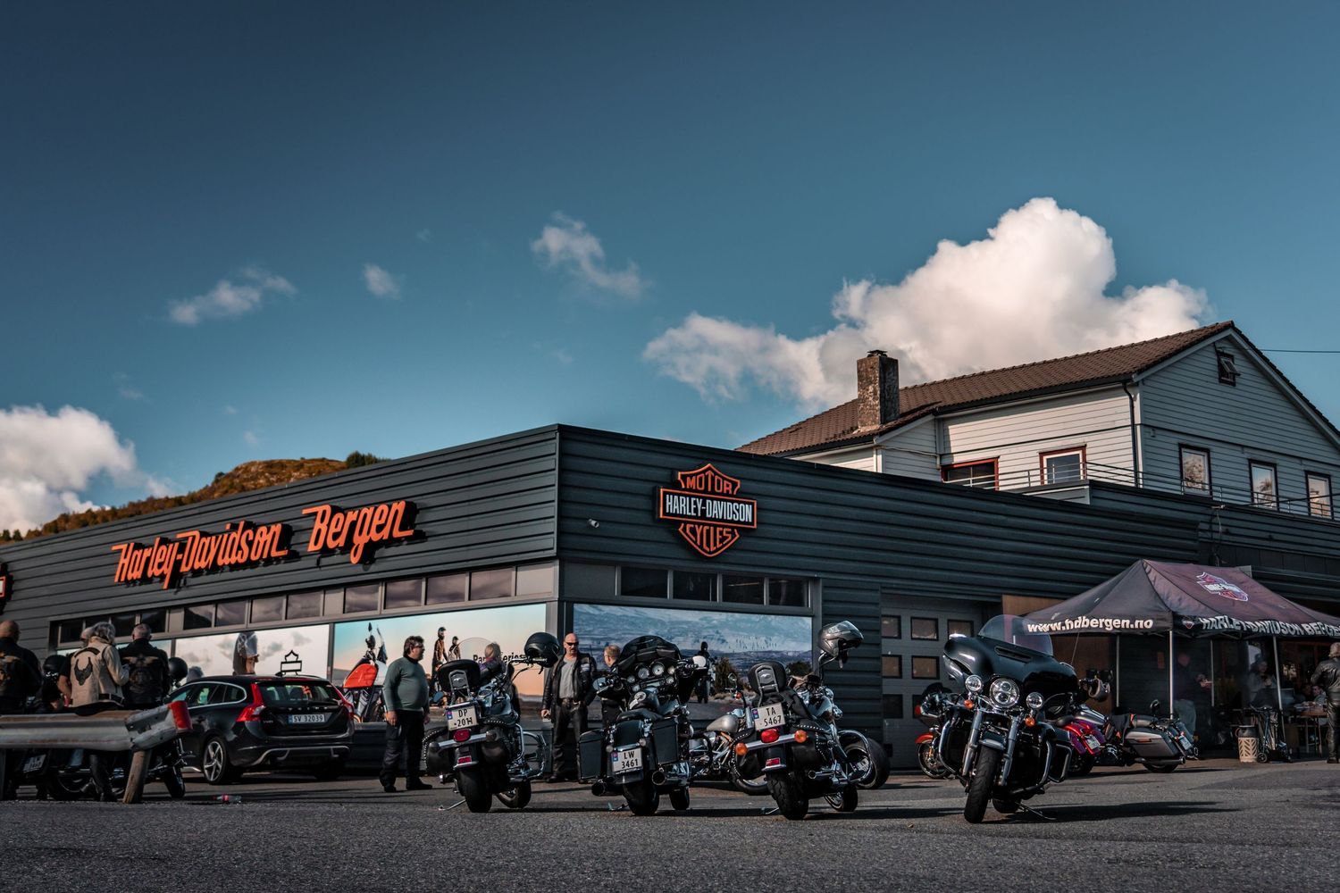 Harley-Davidson dealership exterior with motorcycles parked outside under blue skies.