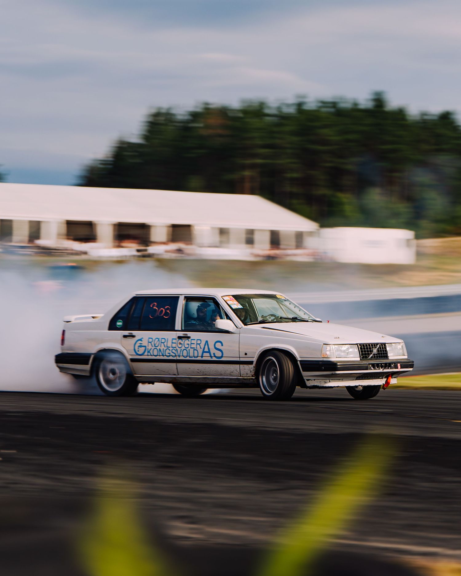 A series of motion-blurred white cars racing on a track, showing dynamic movement and speed during competition.
